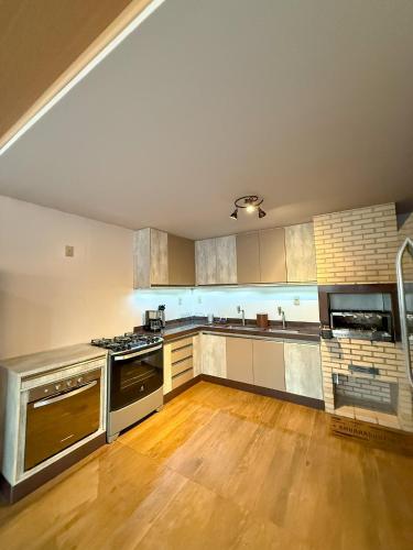 a large kitchen with stainless steel appliances and wooden floors at Luxo Frente Mar em 7 Qtos com Ar sendo 4 suites para até 18 pessoas, 2 Jacuzzi Aquecidas, piscina, brinquedoteca, 5min de Castelhanos in Anchieta