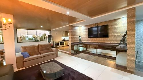 a living room with a couch and a flat screen tv at Luxo Frente Mar em 7 Qtos com Ar sendo 4 suites para até 18 pessoas, 2 Jacuzzi Aquecidas, piscina, brinquedoteca, 5min de Castelhanos in Anchieta
