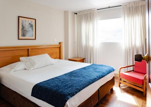 a bedroom with a bed and a red chair at Hotel San Pedro del Fuerte in Medellín