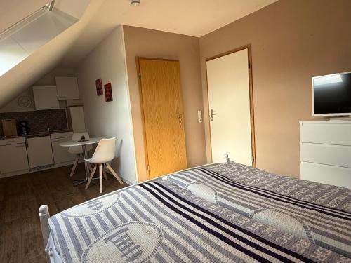 a small bedroom with a bed and a kitchen at Küstenkännchen in Wangerland