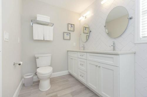 a white bathroom with a toilet and a mirror at The Seaside Retreat, FREE heated pool in Apollo Beach