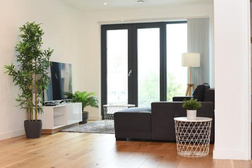a living room with a black couch and some plants at Luxury 2-Bed Apt - Heart of Bham Free Parking in Birmingham