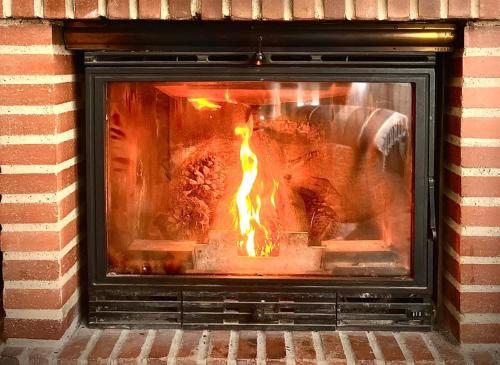 a brick fireplace with a fire in it at Villa de L o L a, Pura Calma & Jakuzzi, a 50 minutos de Málaga y 45 de Córdoba in Lucena