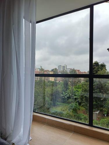 a room with a large window with white curtains at Elegant & Cosy Home in Ruaka