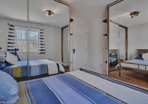 Un dormitorio con dos camas y un gran espejo. en Seabird Apartment, en Portstewart