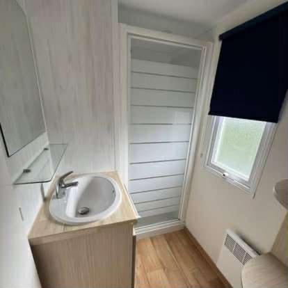 a white bathroom with a sink and a window at Claire's Cottage in Knokke-Heist