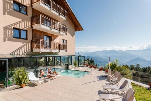 two people sitting in chairs next to a building at Hotel Monte Bondone in Vaneze