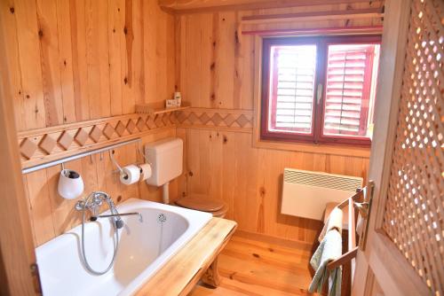 baño con bañera, aseo y ventana en Log cabin Silec, en Šmarje pri Jelšah