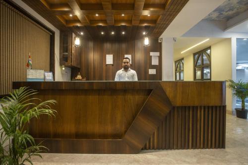 ニューデリーにあるHotel The Best Delhi Airportのロビーの受付デスクに立っている男性