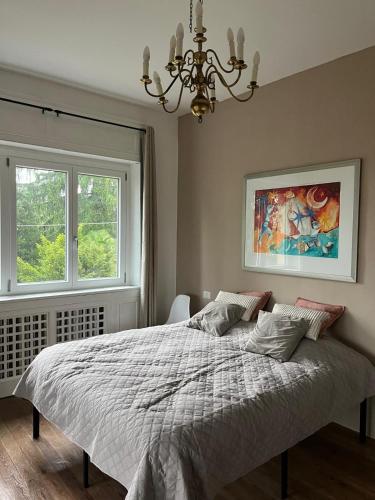 a bedroom with a bed with a chandelier and two windows at Vista Bella - Villa Giulia in Porto Valtravaglia