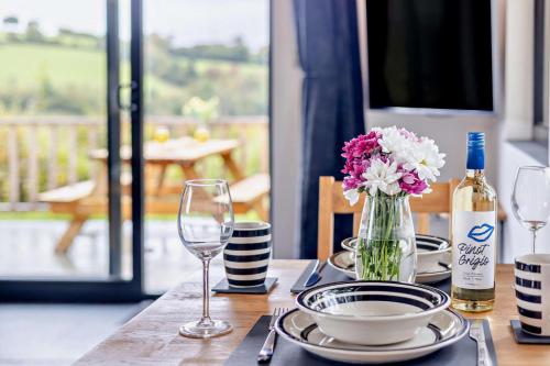 a table with a bottle of wine and a vase of flowers at Derw Bach in Llanfair Caereinion