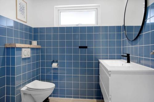 ein blau gefliestes Badezimmer mit Toilette und Waschbecken in der Unterkunft SJ203 Børkop - Bjørnsvej 16 in Børkop