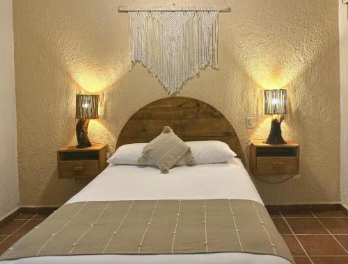 a bedroom with a bed with two night stands and two lamps at Hotel Casa Colibri in Playa del Carmen