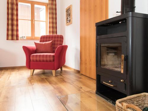a living room with a red chair and a stove at Landhaus Albrecht in Mittenwald