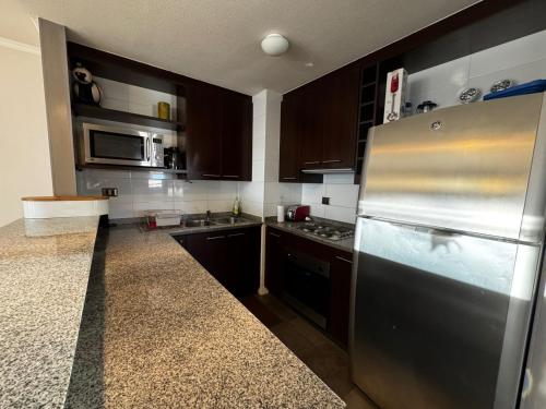 a kitchen with a stainless steel refrigerator and wooden cabinets at HOM I En el Centro SKI Valle Nevado 3D2B SKI IN y OUT in Lo Barnechea