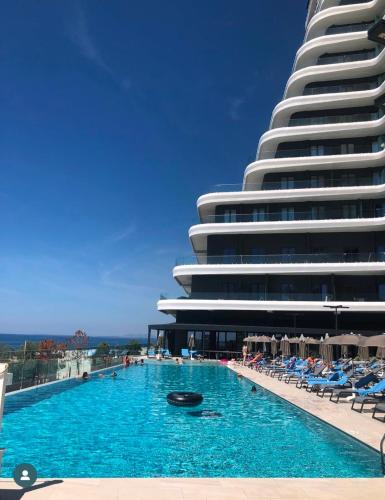 a swimming pool in front of a large building at Mias Apartment - Ilyonis Residence in Shëngjin