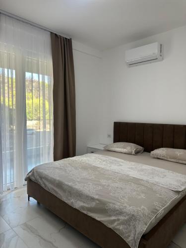 a bedroom with a large bed with a window at Mias Apartment - Ilyonis Residence in Shëngjin