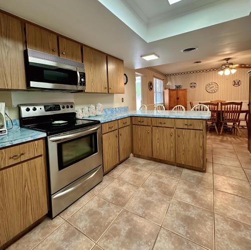 Una cocina con gabinetes de madera y un horno de estufa. en Speed & Sand Pool Table, Parking & Minutes to Beach Or Speedway, en South Daytona