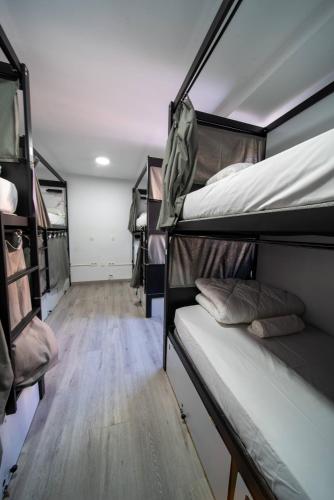 a room with two bunk beds and a wooden floor at Be Happy Hostel - Albergue en el centro de Nerja in Nerja