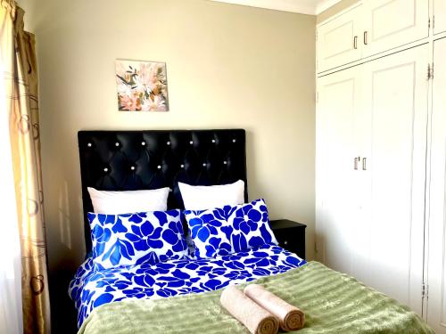 a bedroom with a bed with blue and white pillows at Apartment at Jenner in Windhoek