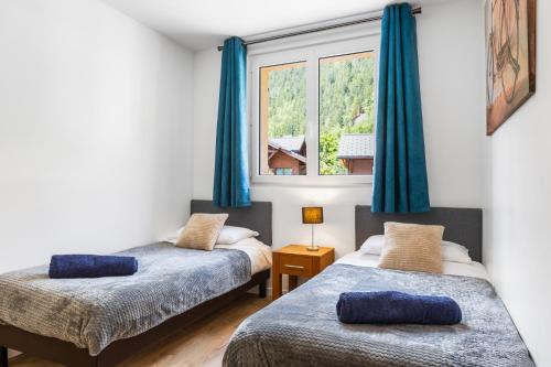 two beds in a room with a window at Apartment Le Panoramic in Chamonix