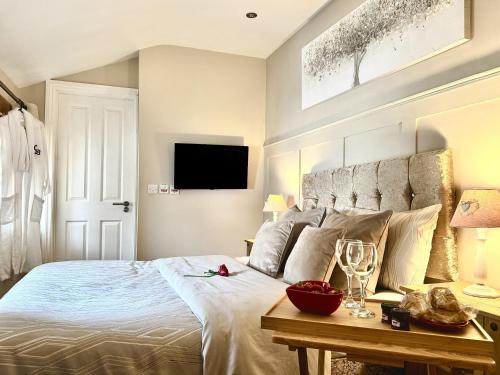 a bedroom with a bed and a table with wine glasses at Caner Bach Lodge in Bridgend