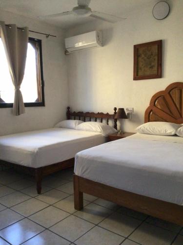 a bedroom with two beds and a window at Hotel Villa Tulipanes in Zihuatanejo