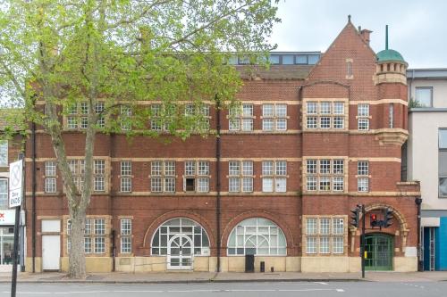 an old red brick building with white windows at Canning Town Serviced Apartment in London