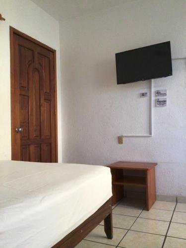a bedroom with a bed and a tv on the wall at Hotel Villa Tulipanes in Zihuatanejo