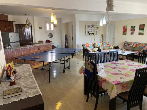 a living room with tables and chairs and a kitchen at شالية 180م بالروف 180م قرية هليوبيتش الساحل الشمالي للايجار للعائلات فقط in Dawwār ‘Abd al Qādir Qāsim