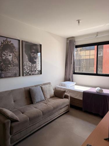 una sala de estar con un sofá y una cama en LK Santa Efigênia 2, en Belo Horizonte