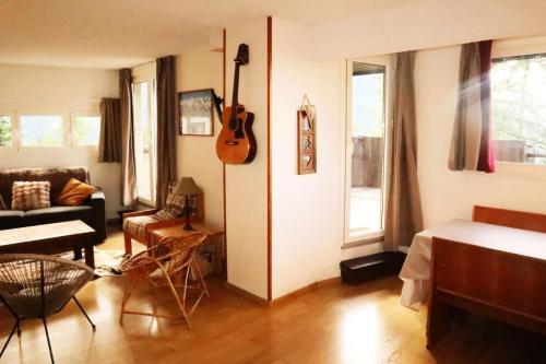a living room with a guitar hanging on the wall at Résidence La Mazeliere - Appartement pour 8 personnes entièrement rénové MAE-3794 in Le Mélézet