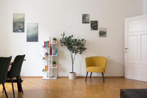 a living room with a yellow chair and a book shelf at Bright City Apartment in Graz