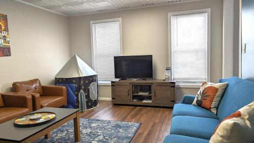 a living room with a blue couch and a tv at Gray Goose - Close to Falls & Casino in Niagara Falls