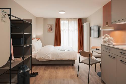a bedroom with a bed and a desk and a kitchen at Stay Sunday in Zürich
