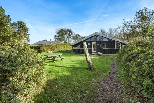 a black cabin with a picnic table in the yard at LL253-Tranekaer-Engvej-1-B in Tranekær
