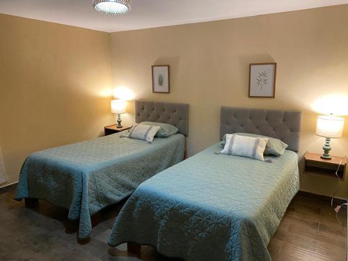 two beds in a hotel room with two lamps at Villa Ojo de Agua in Hacienda Ojo de Agua