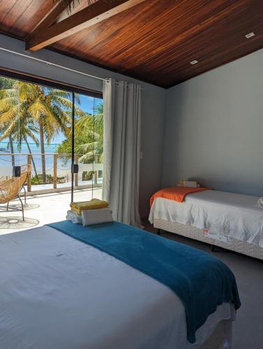 a bedroom with a bed and a view of the ocean at Slater's House in Paripueira