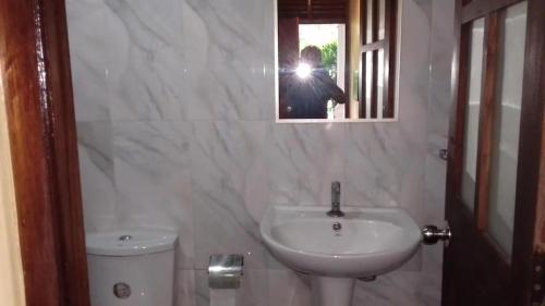 a person taking a picture of a bathroom with a sink at LEAF resorts in Gampola
