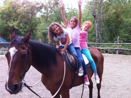 two girls riding on a horse with their hands in the air at Tenuta dei Cavalieri in Molino del Piano