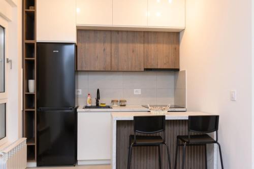 a kitchen with a black refrigerator and two bar stools at Tesla Apartments 1 in Kragujevac