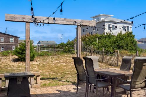 a wooden table and chairs with a table and a bench at 4018 - Shorely Bliss in Kitty Hawk