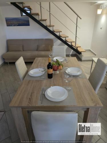 a wooden table with white plates and wine glasses at ALETNA Home in Ragalna