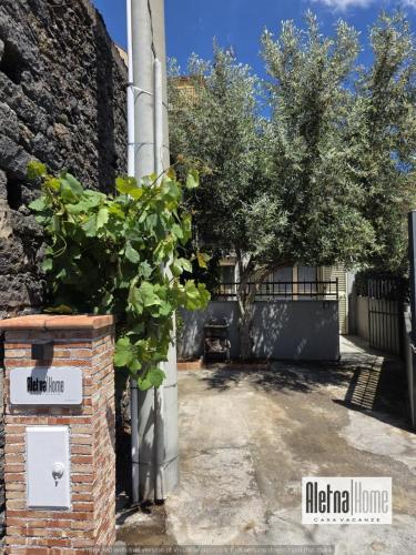 a brick pillar with a tree next to a building at ALETNA Home in Ragalna