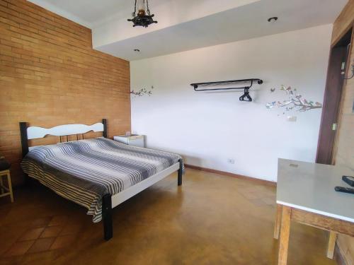 une chambre avec un lit et un mur de briques dans l'établissement Suites da Cla - Suite 1, à Lima Duarte