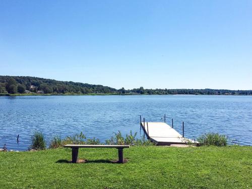 a bench sitting next to a lake with a boat at 3 person holiday home in HÖLLVIKEN-By Traum in Höllviken