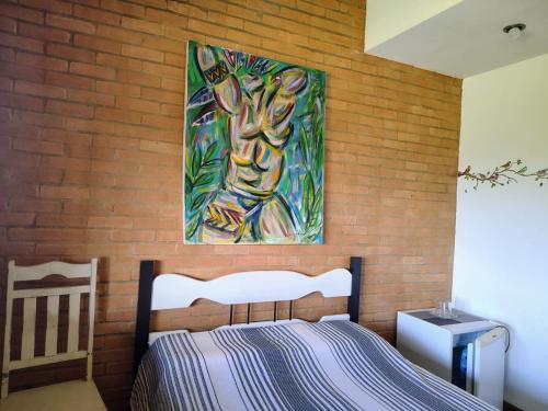 une chambre avec un lit et un tableau au mur dans l'établissement Suites da Cla - Suite 1, à Lima Duarte