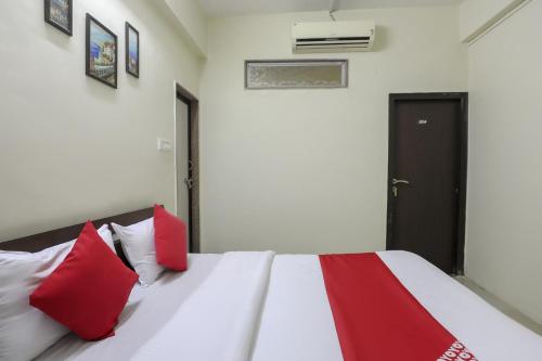 a bedroom with a white bed with red pillows at Hotel O Shyam Vatika Banquet And Rooms in Surat