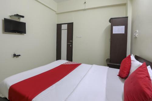 a bedroom with a bed with red and white sheets at Hotel O Shyam Vatika Banquet And Rooms in Surat