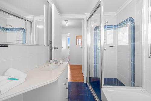 a white bathroom with a shower and a sink at Heritage 401 in Tuncurry